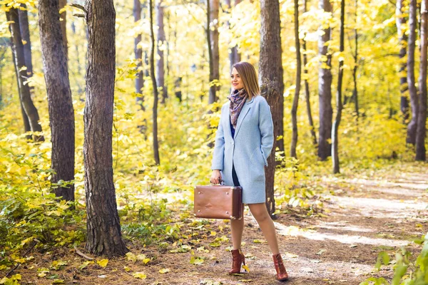 Outono, natureza e conceito de pessoas - Jovem mulher bonita andando no parque com mala — Fotografia de Stock