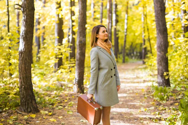 Temporada, natureza e conceito de pessoas - Mulher no parque de outono andando com mala retro — Fotografia de Stock