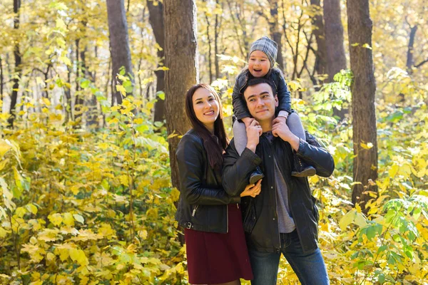 Rodina, podzimní, lidé koncept - mladá rodina v podzimním parku. Dcera na tatínky ramena — Stock fotografie