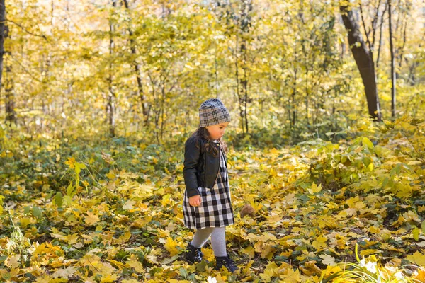 Fall, barndom, människor koncept - liten lycklig flicka promenader i höst park — Stockfoto