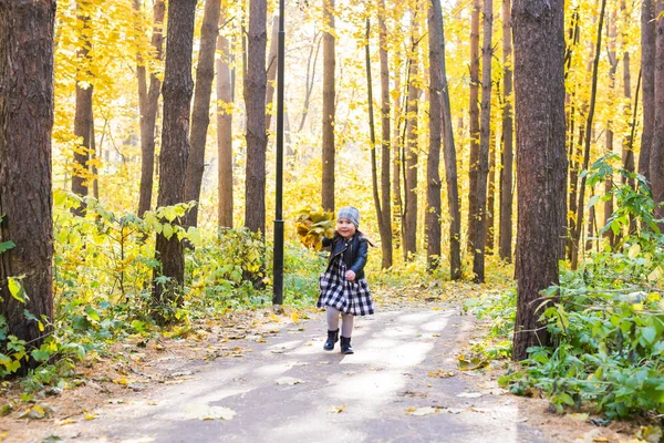 Φθινόπωρο, ευτυχία και άνθρωποι της έννοιας - παιδί διατρέχει φθινόπωρο πάρκο με κίτρινο αφήνει στα χέρια της — Φωτογραφία Αρχείου