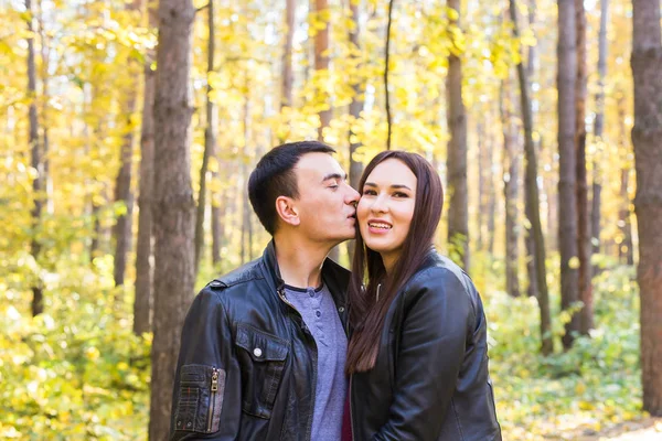 Amor, relación, familia y concepto de personas - hombre besando a su esposa en el parque de otoño — Foto de Stock