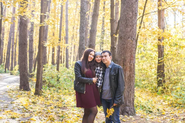 Concept de personnes, famille et loisirs - famille avec une jeune fille marchant dans le parc d'automne — Photo