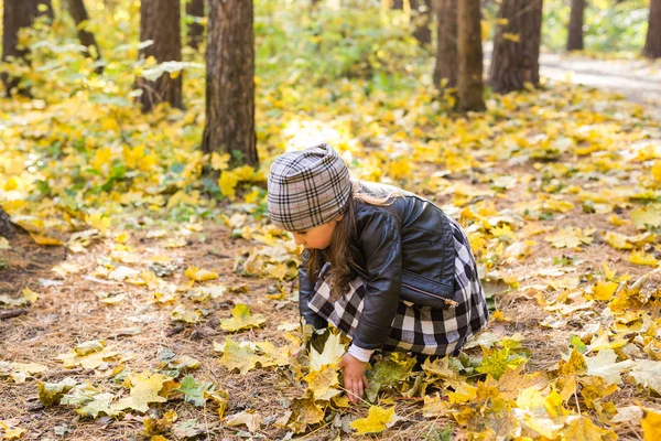 Crianças, outono e conceito de família - menina brincando com folhas caídas no parque — Fotografia de Stock