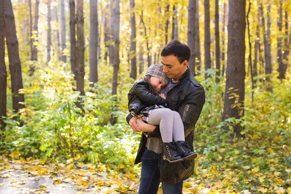 Family, autumn, people concept - father and daughter walking in autumn park. Daughter on dads hands