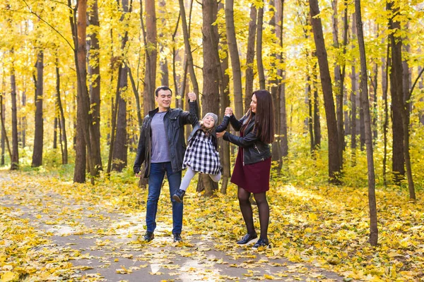 Persone, famiglia e concetto di svago - famiglia felice con figlia che cammina nel parco autunnale — Foto Stock