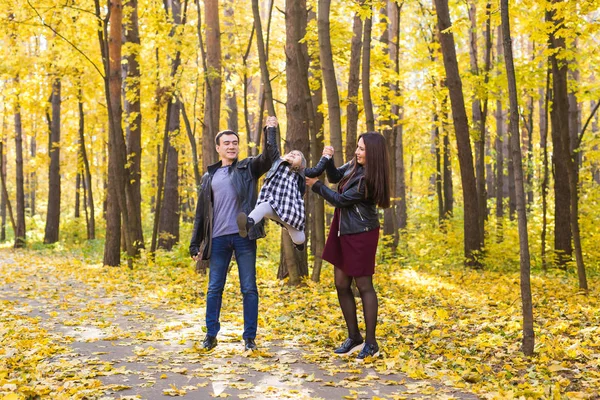 Persone, famiglia e concetto di svago - famiglia con una giovane figlia che cammina nel parco autunnale — Foto Stock