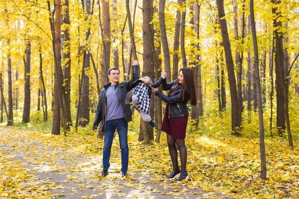 Family, fall, people concept - mixed race young family walking in park on in autumn day