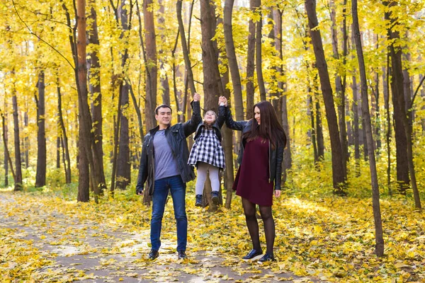 Люди, семья и концепция отдыха - мама, папа и маленькая дочь веселятся в осеннем парке — стоковое фото