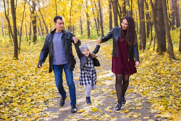 Concepto de personas, familia y ocio: madre, padre e hija se divierten en el parque de otoño —  Fotos de Stock