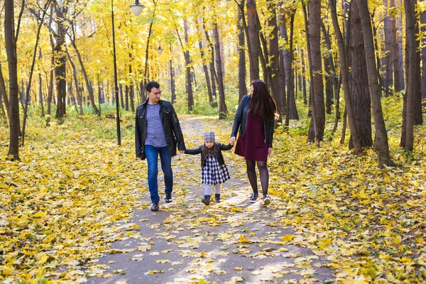 Mensen, familie en vrije tijd concept - familie met een jonge dochter wandelen in de herfst park — Stockfoto