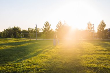 Güzel bir kadınla yeşil çim alan kızı ve bebek evlat. Açık havada yürüyüş iki küçük çocuk anne. Mutlu aile kavramı