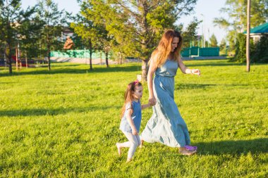 Aile ve çocuk kavramı - anne ve parkta yürüyüş ve güzel doğa kızı.