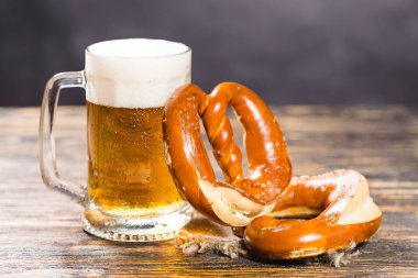 İçecek ve gıda kavramı - bardak bira ve simit ahşap masa üzerinde