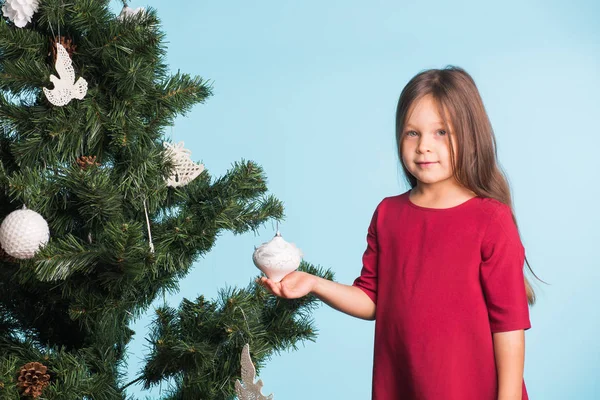 Kleines Mädchen mit Weihnachtsbaum auf blauem Hintergrund — Stockfoto