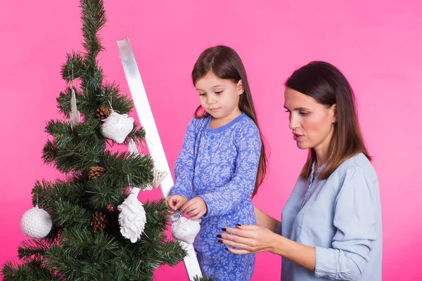 Młoda Mama i jej córka z choinki na różowym tle — Zdjęcie stockowe