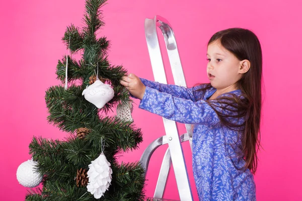 Little girl with christmas tree on pink background — Stock Photo, Image