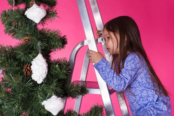 Dzieci, święta i świąteczne koncepcja - mała dziewczynka dekorowanie choinki na różowym tle — Zdjęcie stockowe