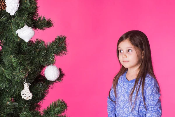 Julen, barndomen och människor koncept - liten flicka titta på granen över rosa bakgrund — Stockfoto