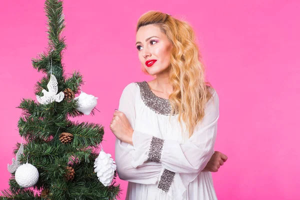 Χριστούγεννα και άνθρωποι έννοια - νεαρός ξανθιά γυναίκα που σκέφτομαι επόμενο έτος κοντά το χριστουγεννιάτικο δέντρο σε ροζ φόντο — Φωτογραφία Αρχείου