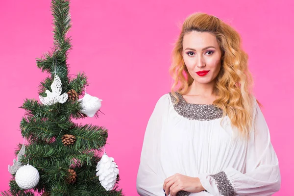 Χριστούγεννα, διακοπές και άνθρωποι έννοια - ευτυχισμένη γυναίκα κοντά στο χριστουγεννιάτικο δέντρο σε ροζ φόντο — Φωτογραφία Αρχείου