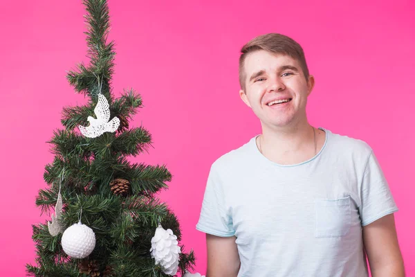 Pessoas, feriados e conceito de Natal - jovem homem sorridente perto da árvore de Natal em fundo rosa — Fotografia de Stock