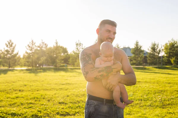 Feliz padre sosteniendo bebé hijo en la naturaleza. Concepto de familia feliz, día del padre y el niño . — Foto de Stock