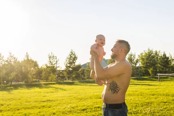 Feliz padre sosteniendo bebé hijo en la naturaleza. Concepto de familia feliz, día del padre y el niño . — Foto de Stock
