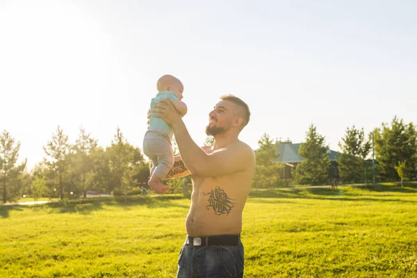 Buon padre che tiene in braccio il bambino, che lancia il bambino in aria. Concetto di famiglia felice, giorno di padri e bambino . — Foto Stock