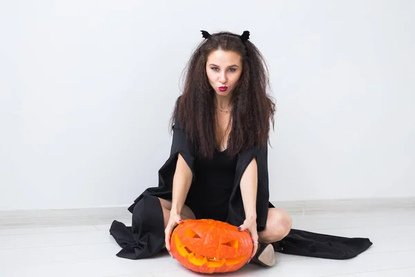Porträt einer stilvollen brünetten Frau mit Halloween-Kürbis Stockfoto
