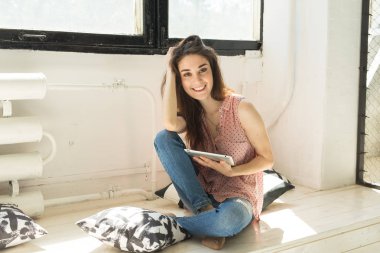 Eğlence, teknoloji ve insan kavramı - genç esmer kadın evde tablet kullanma