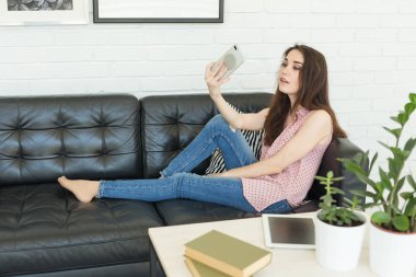 Teknoloji, fotoğraf ve insanlar kavramı - karanlık kanepede yatan bir selfies alarak genç kadın