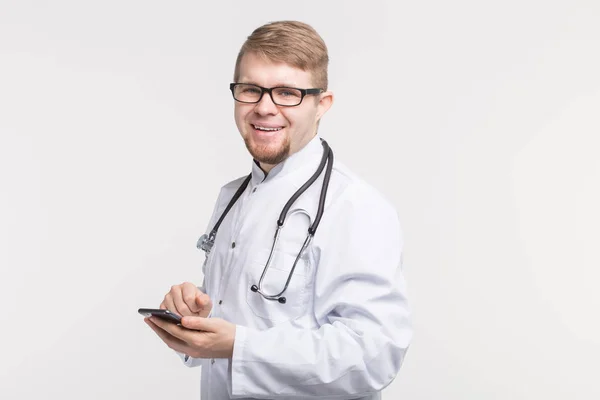 Portrait of male doctor with smartphone in hands on white background — Stock Photo, Image