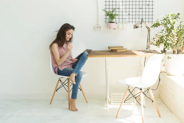 Tecnologie, comunicazione, concetto di persone - la giovane donna è seduta sulla sedia e utilizza tablet digitale — Foto Stock