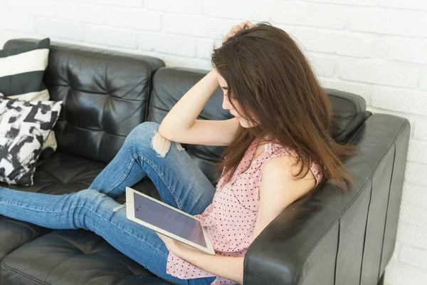 Tecnologie, concetto di persone - giovane donna seduta sul divano e che guarda il portatile o naviga in rete — Foto Stock