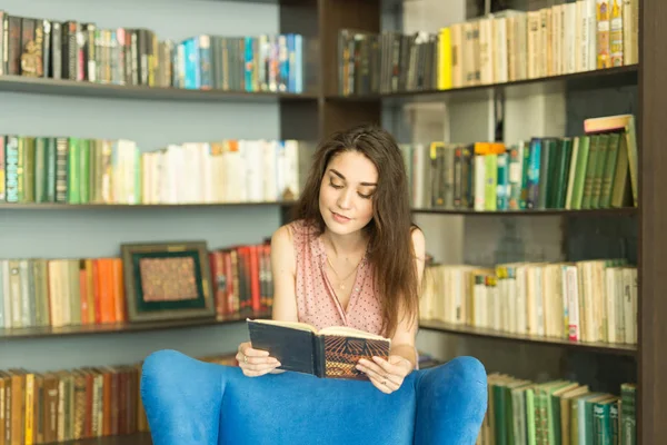 Persone, istruzione e concetto universitario - giovane studentessa con un libro in biblioteca — Foto Stock