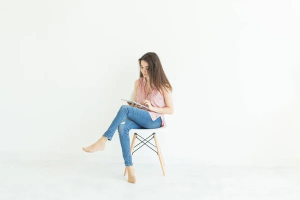Persone, tecnologia e concetto di istruzione - giovane studentessa seduta su una sedia e che utilizza un tablet su sfondo bianco con spazio per la copia — Foto Stock