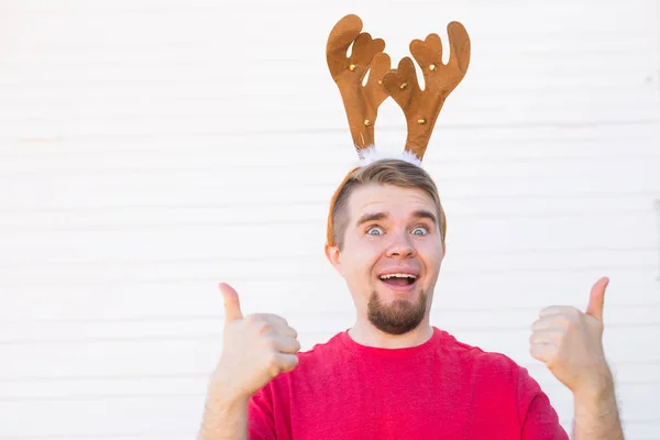 Concepto de vacaciones y Navidad - Joven con cuernos de ciervo con el pulgar hacia arriba gesto sobre fondo blanco —  Fotos de Stock