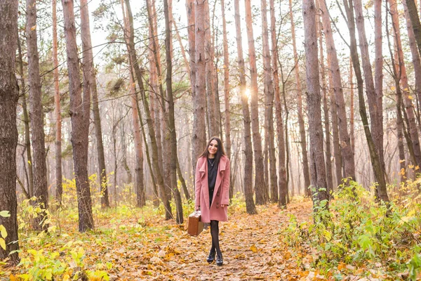 Sonbahar, Doğa ve insan kavramı - bavul ile parkta yürüyen genç güzel kadın