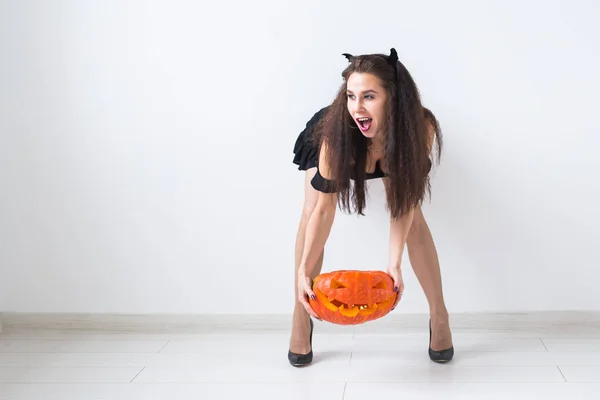 Porträt einer stilvollen brünetten Frau mit Halloween-Kürbis über hellem Hintergrund mit Kopierraum — Stockfoto