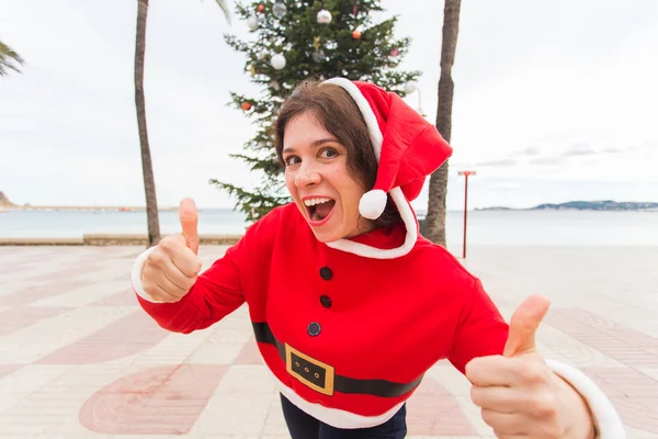 Yılbaşı, bayram, mizah ve insanlar kavramı-genç mutlu kadın yaz başparmak göstermek yukarıya vasıl Noel kıyafetli — Stok fotoğraf