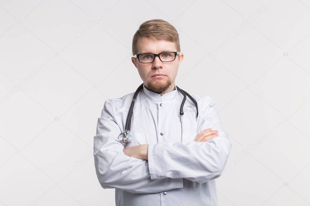 Studio portrait of handsome white young doctor men in glasses and white medical gown with stethoscope