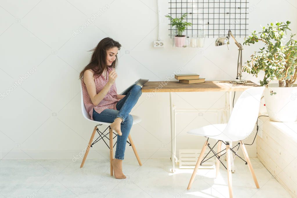 Technologies, communication, people concept - young woman is sitting on chair and using digital tablet