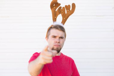 Noel, insanlar, duygular kavramı - memnun kızgın adam Noel geyik boynuzları görüntüleyiciyi işaret