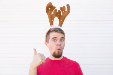 Tatil ve Noel kavramı - genç erkek geyikler boynuzları ile jest beyaz arka plan üzerinde yukarı şaşırttı