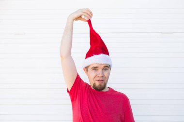 Bayram, yılbaşı ve insanlar kavramı - komik yakışıklı Noel Baba şapkası var eğlenceli beyaz arka plan üzerinde