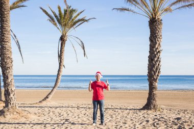 Noel, insanlar, tatil kavramı - sahilde başparmak gösterilmesini Santa şapka adam