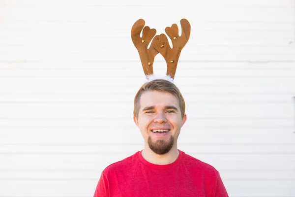 Feestdagen en Kerstmis concept - gelukkig jongeman in herten hoorns op witte achtergrond — Stockfoto