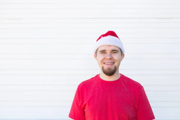 Vacaciones, Navidad y el concepto de la gente - retrato de hombre guapo divertido en sombrero de santa divertirse sobre fondo blanco con espacio para copiar — Foto de Stock
