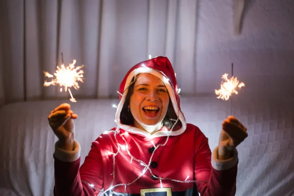 Vacances, Noël et les gens concept- Jeune femme heureuse en costume de Père Noël avec des étincelles — Photo